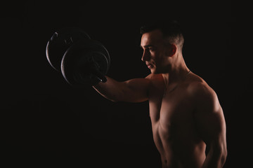 Fototapeta na wymiar Photo of young man working at his biceps with dumbbells