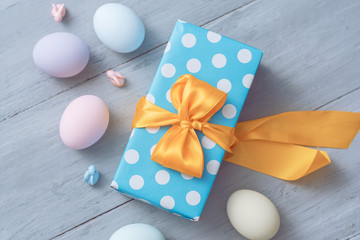 easter eggs and gift box with beautiful bow on wooden gray background
