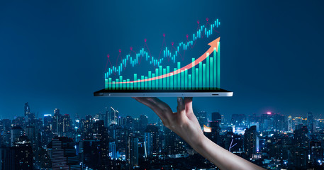 Business evolution to success and growing growth concept.hand holding an empty digital tablet with growth stock graph and rising arrow,Corporate representing business growth on city background.