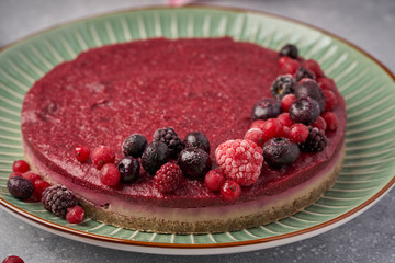 Raw vegan berry cherry cheesecake gluten-free on grey background.