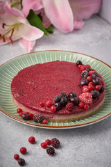Raw vegan berry cherry cheesecake gluten-free on grey background.