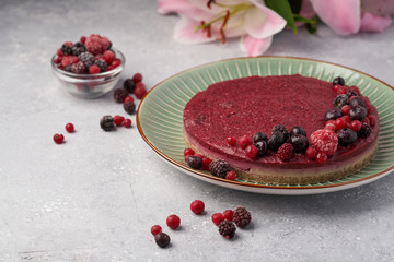 Raw vegan berry cherry cheesecake gluten-free on grey background.