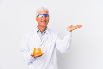 Mature chemical man isolated showing a copy space on a palm and holding another hand on waist.