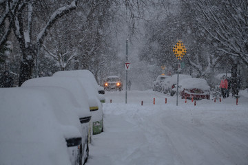City road street and cars during snow storm cover in deep powder with heavy snowfall in Vancouver Canada British Columbia Canadian winter cars covered in snow 