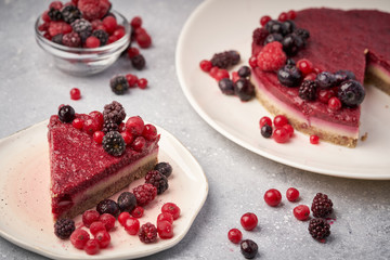 Raw vegan berry cherry cheesecake gluten-free on grey background.