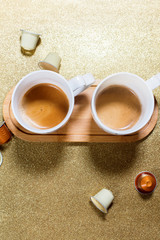 Two cups espresso coffee and capsules on golden