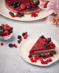 Raw vegan berry cherry cheesecake gluten-free on grey background.