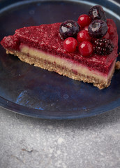 Raw vegan berry cherry cheesecake gluten-free on grey background.