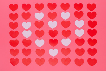 a lot of red small hearts put entire a picture and white small hearts put in a heart pattern, those are put on a pink background