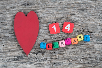 Fototapeta na wymiar colorful cube calendar and heart on wooden background for february