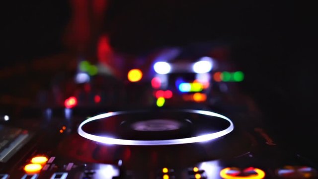 DJ mixing Close up - Camera is moving backwards revealing colorful buttons and creating bokeh