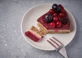 Raw vegan berry cherry cheesecake gluten-free on grey background.