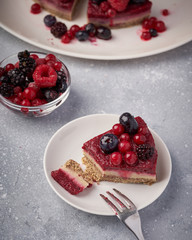 Raw vegan berry cherry cheesecake gluten-free on grey background.