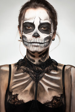 brunette girl with skull makeup for halloween on a black background