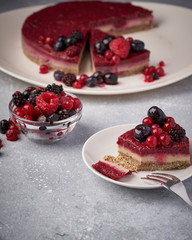 Raw vegan berry cherry cheesecake gluten-free on grey background.