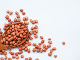 Peanut beans on wooden spoon and white wooden background, is a legume crop grown mainly for its edible seeds, Selective focus.