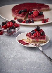 Raw vegan berry cherry cheesecake gluten-free on grey background.