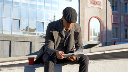 Young male read book outdoorsom the street	