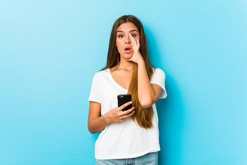 Naklejka premium Young caucasian woman holding a phone shouting excited to front.