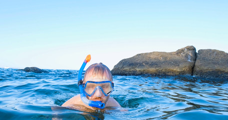 Young male swimmer with snorkling glasses dive in the summer sea	