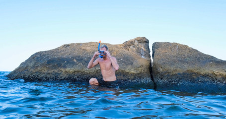 Young male swimmer with snorkling glasses dive in the summer sea	