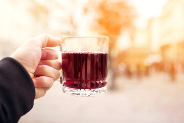 Glass cup with hot mulled wine in a female hand outdoor
