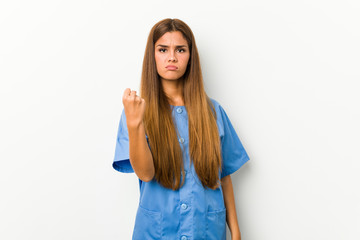 Young caucasian nurse woman showing fist to camera, aggressive facial expression.