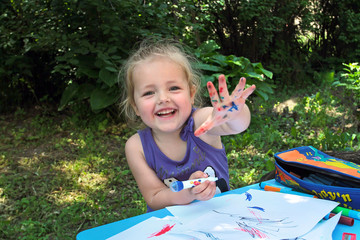 Little girl showing painted palm while drawing.