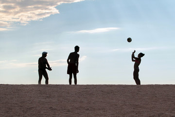 Silhouettes of people playing volleyball on the beach