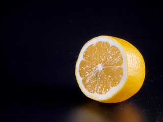 half a yellow fresh lemon on an isolated black background. yellow lemon