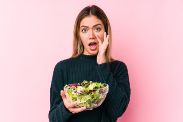 Young caucasian woman holding a salad isolated shouting excited to front.