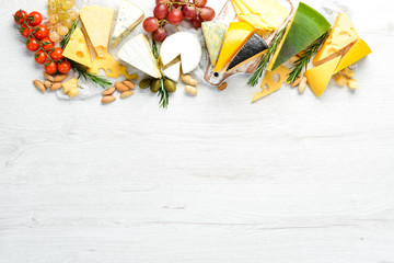 Assorted cheese and snacks on white wooden background. Dairy products. Top view. Free space for your text.