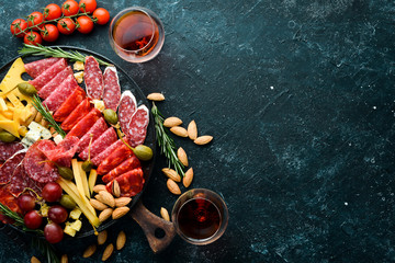 italian antipasti snacks, cheese and wine in glasses. Top view. On a black stone table. Free space for your text.