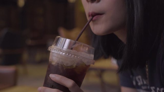 4k young asian adult female sit having a glass of coffee using straw sucking. free time, chillin during the day, americano coffee, stressful at cafe, caffeine, thoughtful, anxiety worries mind