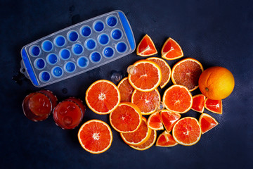 Fresh red orange or grapefruit with ice on a blue classic background. Tropical citrus fruit....