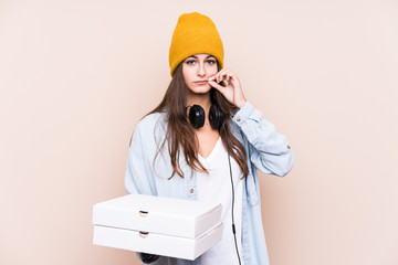 Young caucasian woman holding pizzas isolated with fingers on lips keeping a secret.