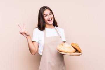 Young caucasian baker woman isolated joyful and carefree showing a peace symbol with fingers.