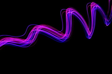 Long exposure light painting, vibrant purple color in abstract swirl against a clean black background.  Light painting photography.