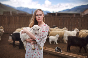 girl in the arms of a lamb farm in the mountains