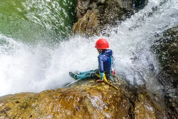 Fotobehang Mutprobe beim Canyoning - Felsrutsche in einen Wasserfall © ARochau