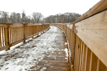 wooden boardwalk trail though winter woods