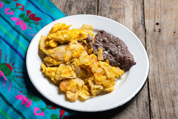Mexican scrambled eggs with corn tortilla also called migas on wooden background