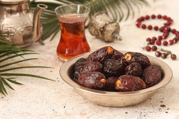 Fresh Medjool Dates in a bowl with tea on light  background. Ramadan kareem.