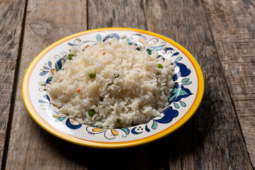 Rice with peas and carrots on wooden background