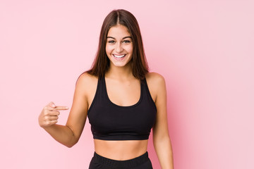 Young caucasian fitness woman doing sport isolated person pointing by hand to a shirt copy space, proud and confident