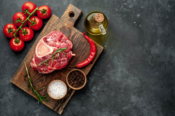 Raw beef steak with tomatoes and spices on a concrete background with copy space for your text. 