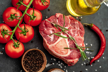 raw beef steak with tomatoes and spices on a stone background. 