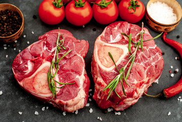 two raw beef steaks with tomatoes and spices on a concrete background with copy .Close-up .Cooking dinner concept for two