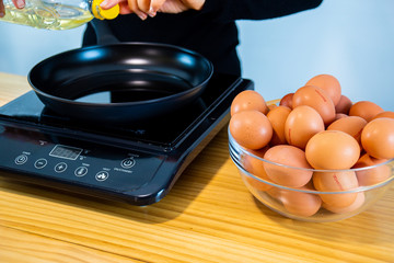 Eggs, oil, black pan and a girl