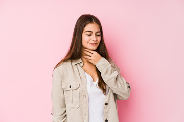 Young caucasian woman posing in a pink background suffers pain in throat due a virus or infection.